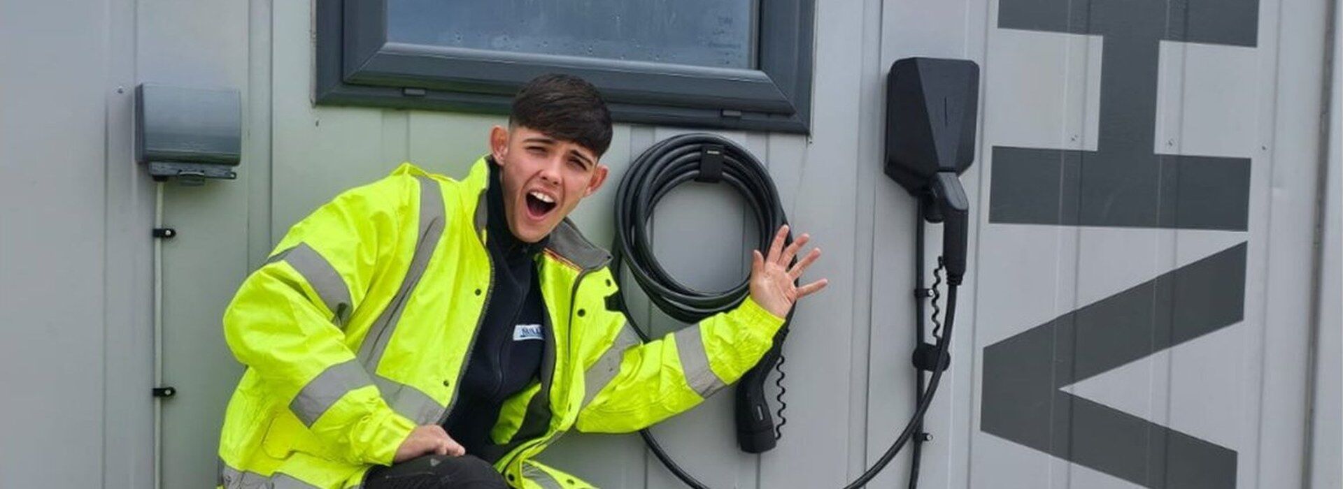 Millar Electrics apprentice electrician beside a newly installed EV charging point